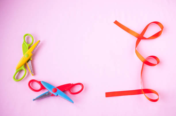 istock Red ribbon and scissors on a pink background 918740458