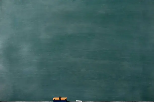 Photo of Smudged blank blackboard with board eraser and chalk