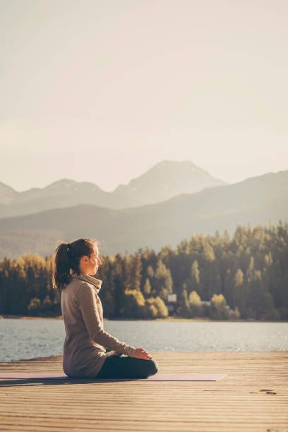 Young woman practicing yoga on dock by the lake. stock photo