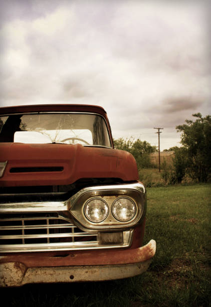 Front end of an Old Pick-up Truck in Country Sepia toned picture with orange accents of an old, broken down pick-up truck in a field in the country. distressed rusty vintage pickup truck close up detail stock pictures, royalty-free photos & images