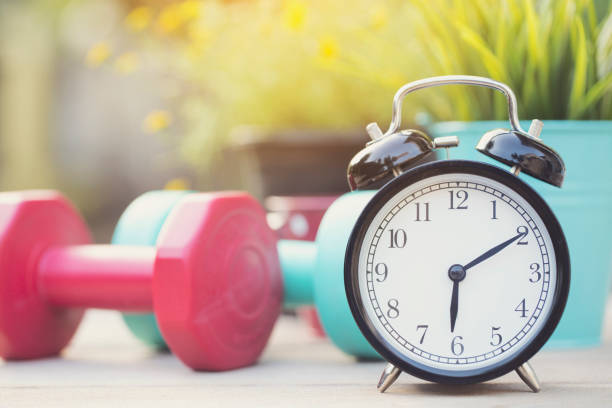 istock Time for exercising clock and dumbbell with colorful background 918757878