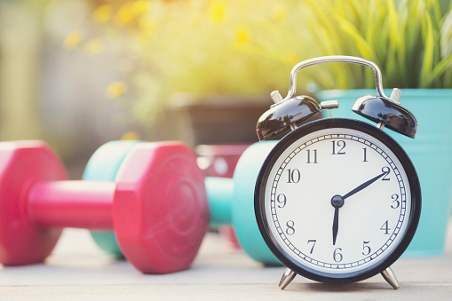 Time for exercising clock and dumbbell with colorful background