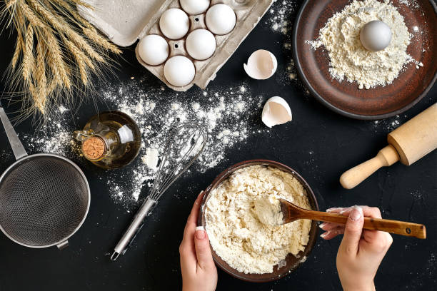 istock Female hands making mixing dough in brown bowl on black table, baking preparation close-up 918763706