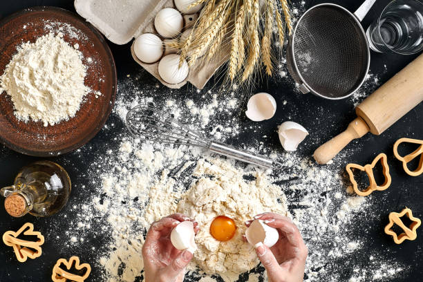 istock Woman smashes an egg using knife while kneading a pastry. Studio shot. Top view 918767174