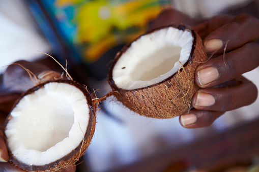 An Afro Caribbean market stall holder shells a coconut to revel its water and flesh