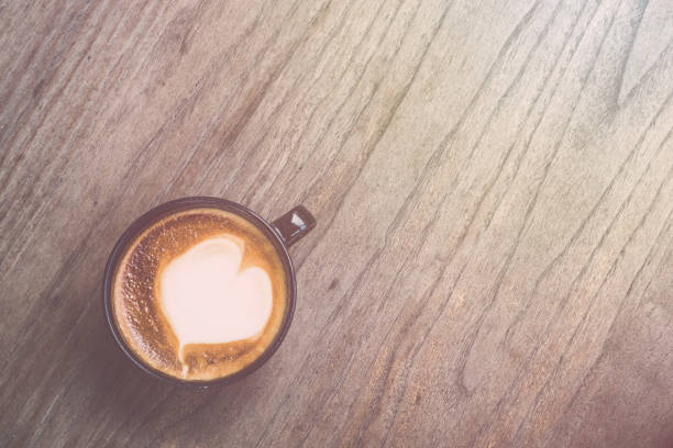 istock Hot latte coffee in black cup on grey wooden table background. Vintage filter effect 918776732