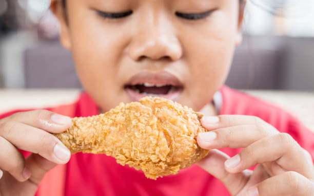 istock Asian children eating fried chicken in the restaurant 918792962