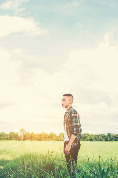 istock young handsome man standing in green field. 918796576