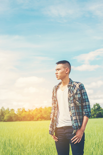 young handsome man standing in green field.