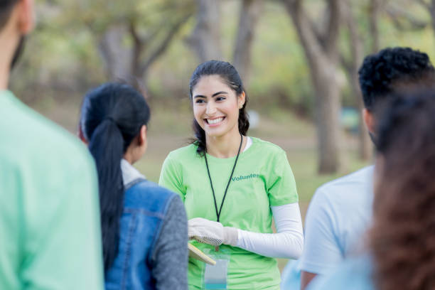 Young woman stands outside and leads volunteer training session