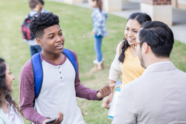 istock Teenage boy gestures while talking with teacher before school 918805722