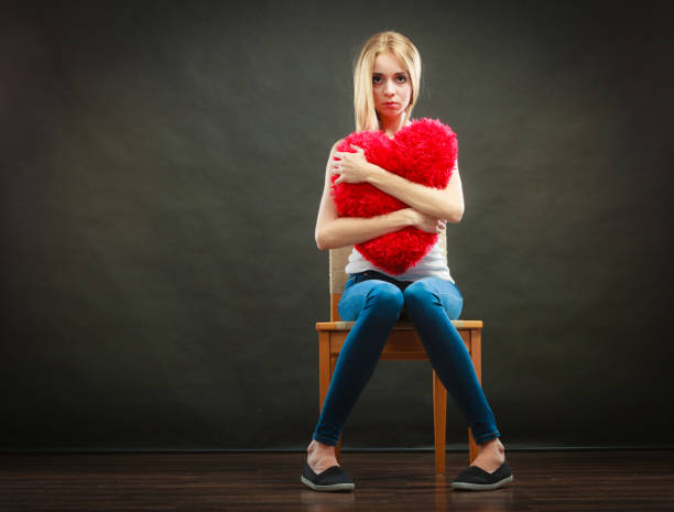 istock Sad unhappy woman holding red heart pillow 918807732