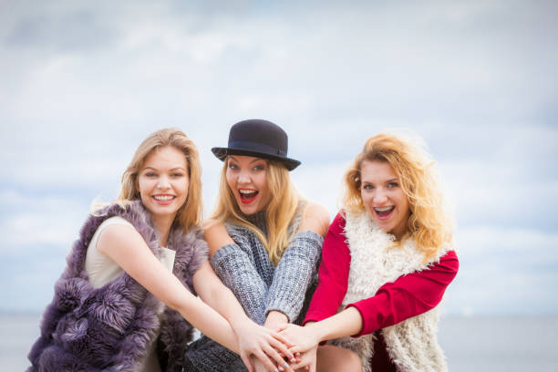 Three fashionable women having presenting pretty stylish outfits. Style, fashion, friendship concept.