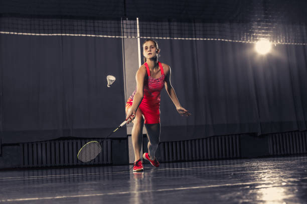 jovem mulher jogando badminton no ginásio - badminton school gymnasium shuttlecock sport - fotografias e filmes do acervo