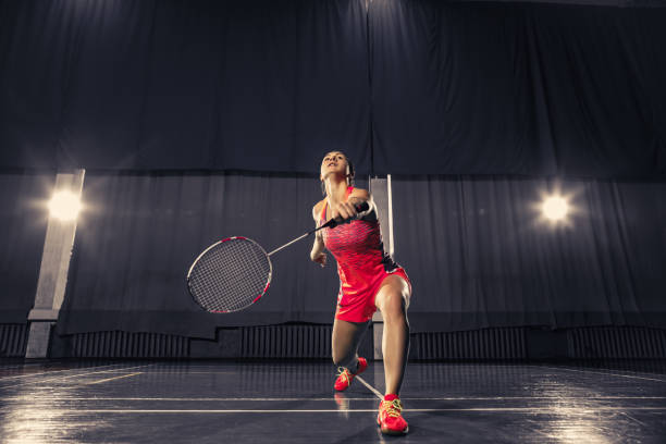 istock Young woman playing badminton at gym 918822252