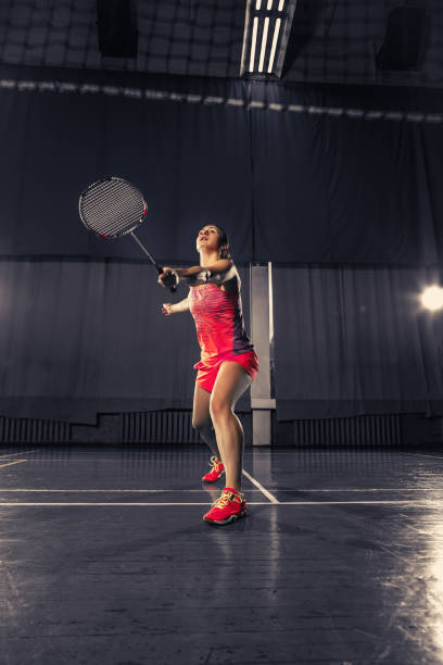 istock Young woman playing badminton at gym 918822266