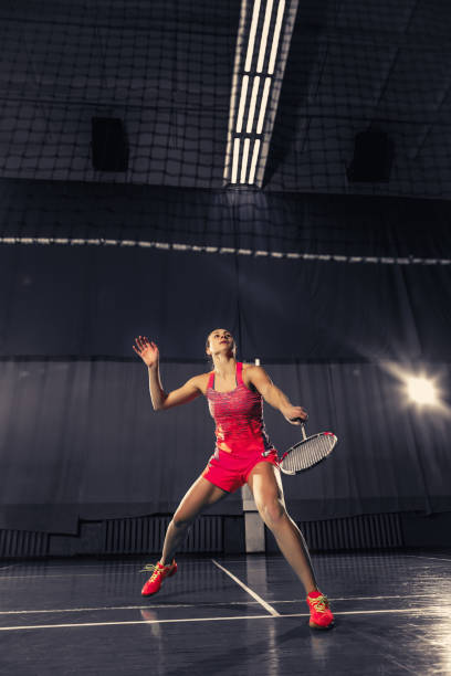 istock Young woman playing badminton at gym 918822792