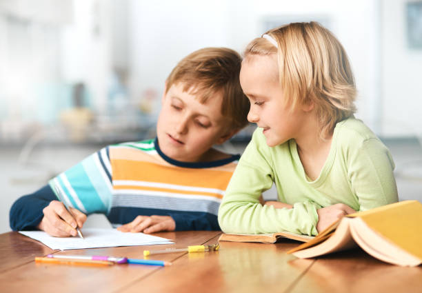 istock Little blonde girl gets homework help from big brother 918825044
