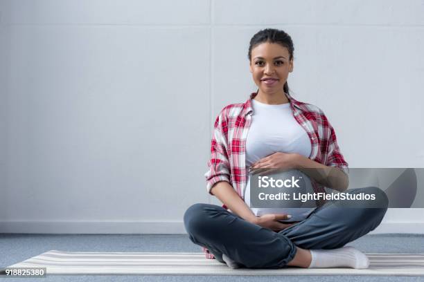 Americana Africano Mujer Embarazada Sentada En La Estera De La Yoga Foto de stock y más banco de imágenes de Embarazada