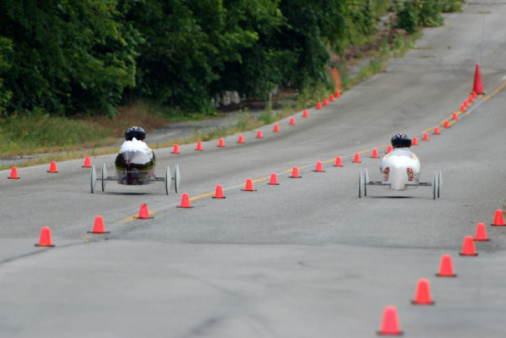 To children race down a soap box derby track.