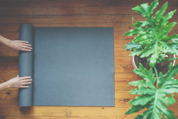 Femme rouler sa natte après un cours d’yoga, vue de dessus - Photo