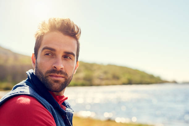 Shot of a thoughtful hiker admiring the view of a lake on a sunny day