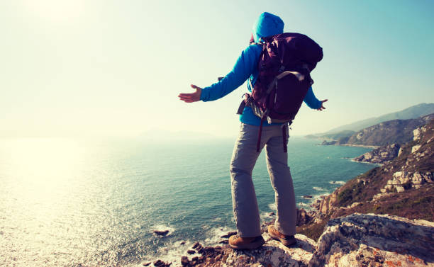 istock Successful female hiker standing on sunrise seaside mountain cliff edge 918850980
