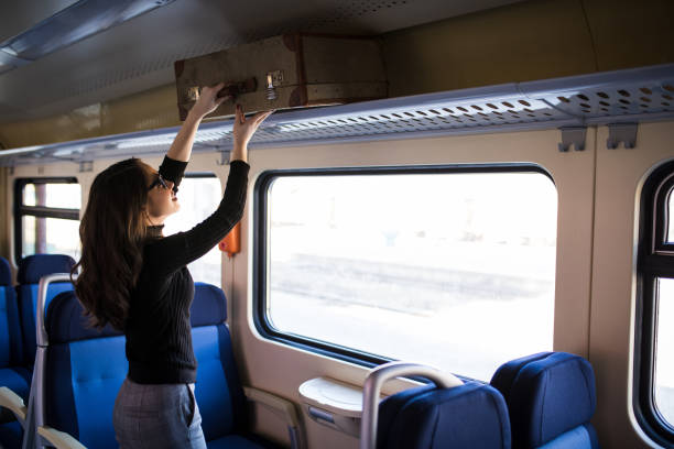 istock Woman putting her baggage on train grid compartment lifting commuter 918855780