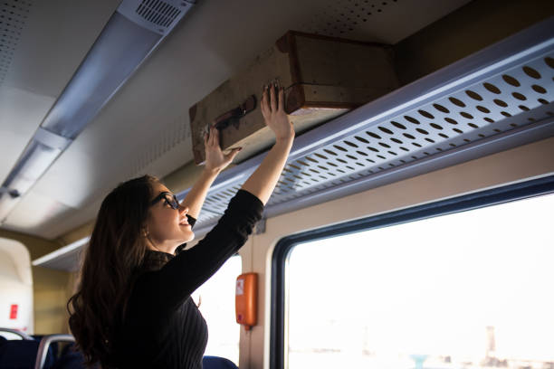 istock Woman putting her baggage on train grid compartment lifting commuter 918856104