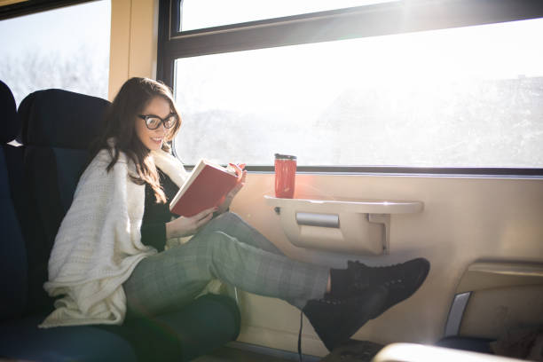 istock Woman reading while traveling with the train commuter journey sitting 918860824