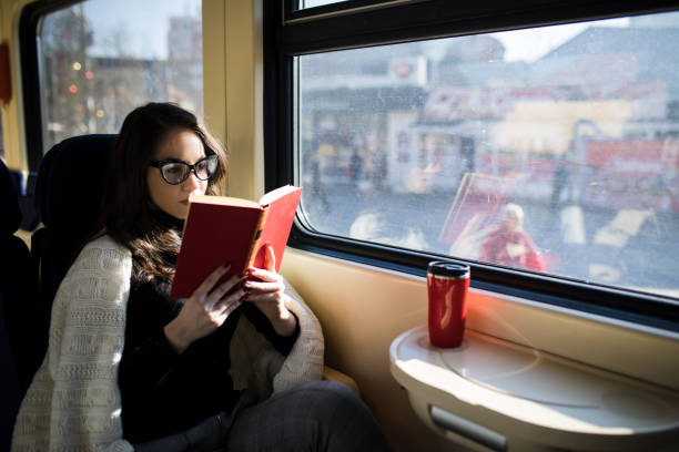 istock Woman reading while traveling with the train commuter journey sitting 918861448