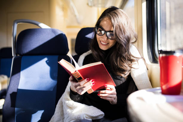 istock Woman reading while traveling with the train commuter journey sitting 918861632