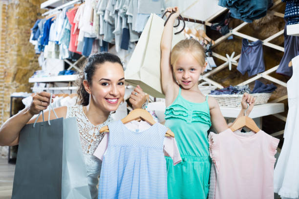 istock Female customer with small girl holding clothes 918861728