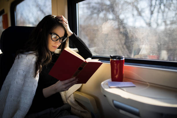 Woman reading while traveling with the train commuter journey sitting stock photo
