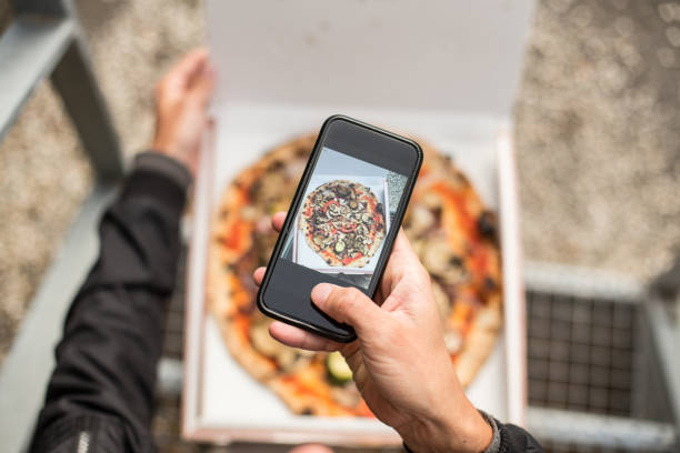 istock Man makes photo of pizza in box 918866452