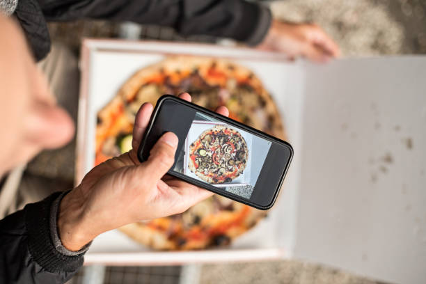 istock Man makes photo of pizza in box 918868668
