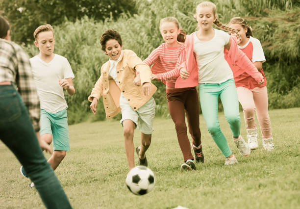 istock Cheerful children are jogning with ball 918876192