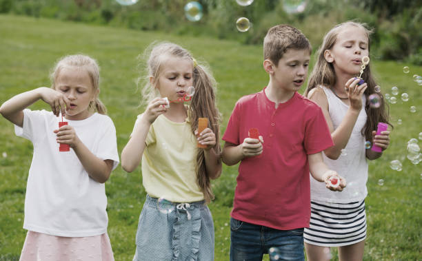 istock children blowing bubbles in park 918876352