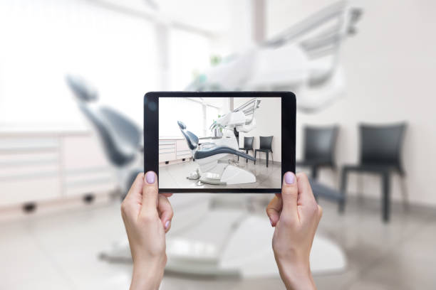 Touchpad & dental office Horizontal color image of female hands holding digital tablet, dentist's chair and dental equipment. tablet pc and digital hospital tools stock pictures, royalty-free photos & images