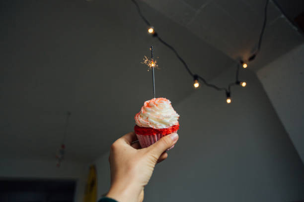 istock Hand holds pink sweet cupcake with sparkle 918877330