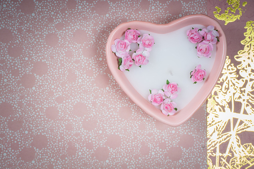 Decoration for Valentine's Day: pink heart shaped candle with little artificial flowers