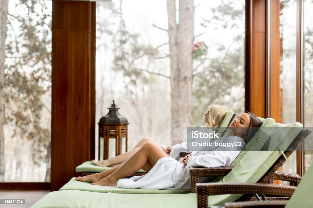 Pretty young women relaxing on the deckchair by the swimming pool Pretty young women relaxing on the deckchair by the swimming pool in spa Spa Stock Photo