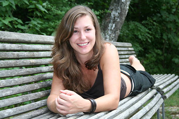 Girl is posing on bench in her free time in the park.