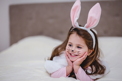 Cute toddler girl wearing a bunny ears at home during Easter celebration.