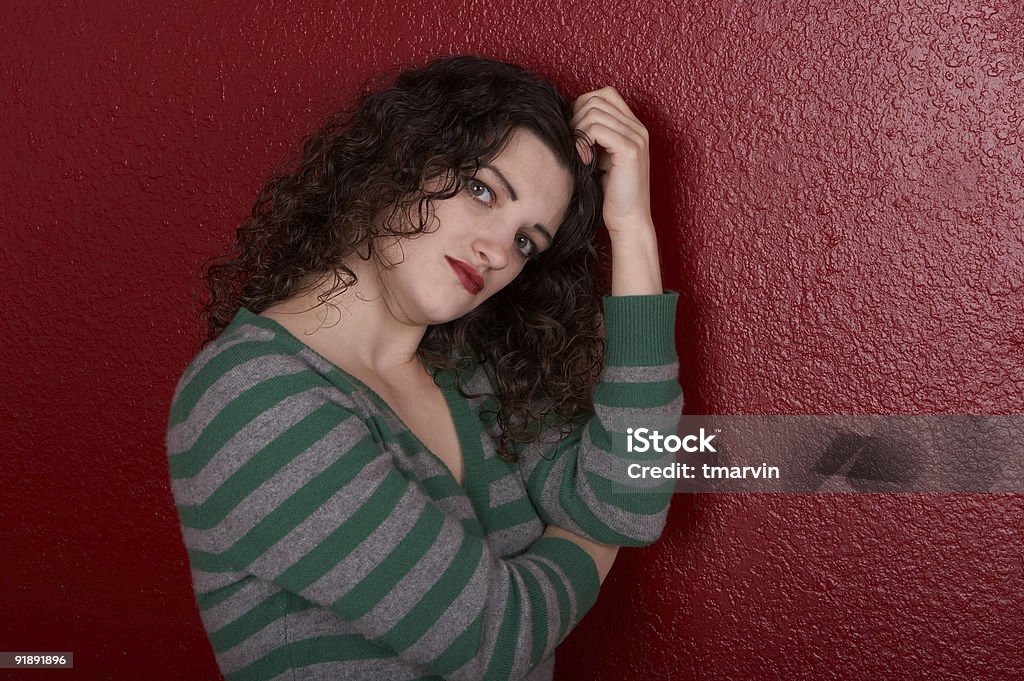 Green and red An attractive young woman leaning against a red wall. Achievement Stock Photo