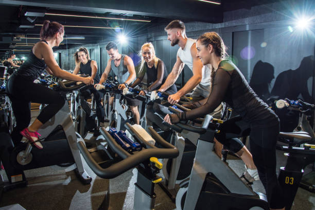 매력적인 여자와 남자는 체육관에서 고정 자전거에 페달의 그룹. - spinning instructor exercising gym 뉴스 사진 이미지