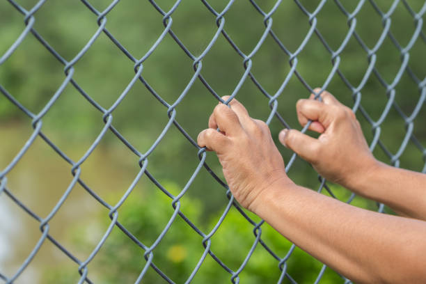 istock Hand hanging on metal chain link fence 918937812