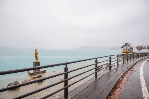 View of Tazawa lake with statue of the Tatsuko on rainy day in Akita prefecture ,Tohoku , Japan.