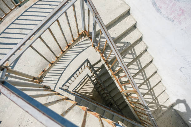 istock Old concrete spiral staircase with a rusty railing, the view from the top. 918939374