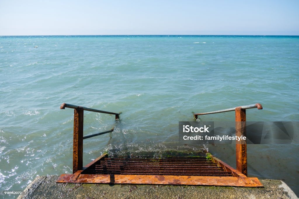 Rusty metal staircase descends into the sea from the pier. Top view. Rusty metal staircase descends into the sea from the pier. Top view Backgrounds Stock Photo